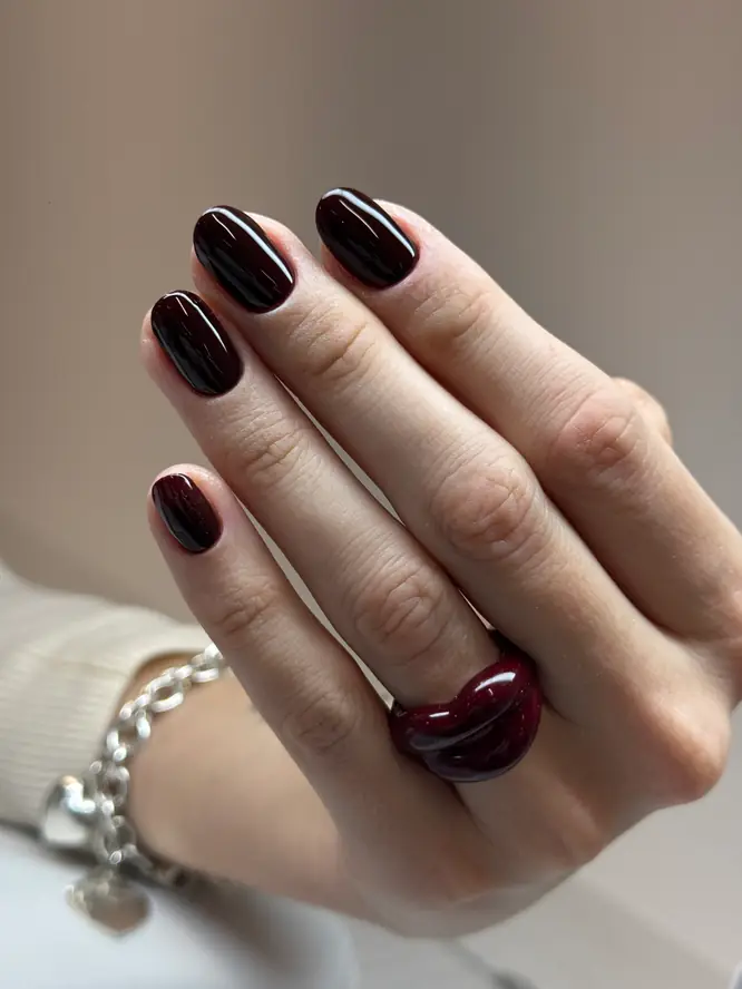 Black-cherry gel gloss on short round nails — client manicure.