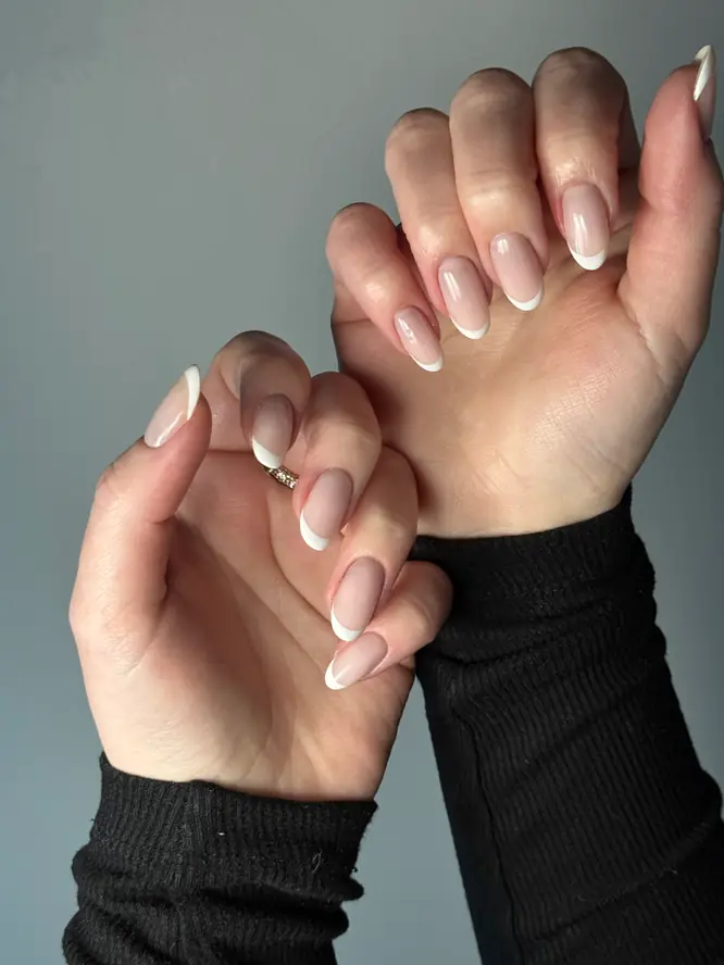 Classic French manicure on almond nails, both hands — salon work.