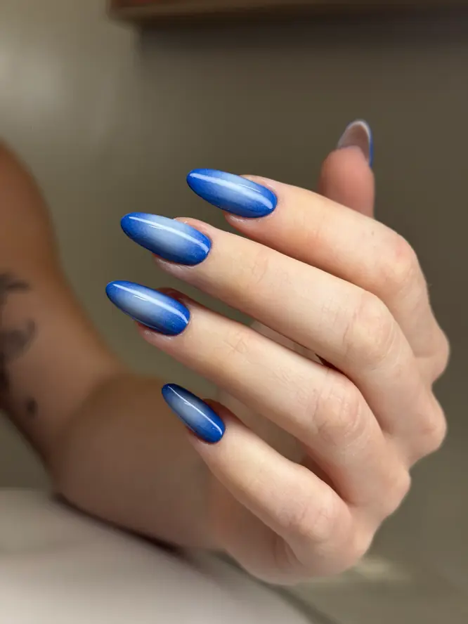Cobalt-blue ombré cat-eye gel on almond nails — second angle, client work.