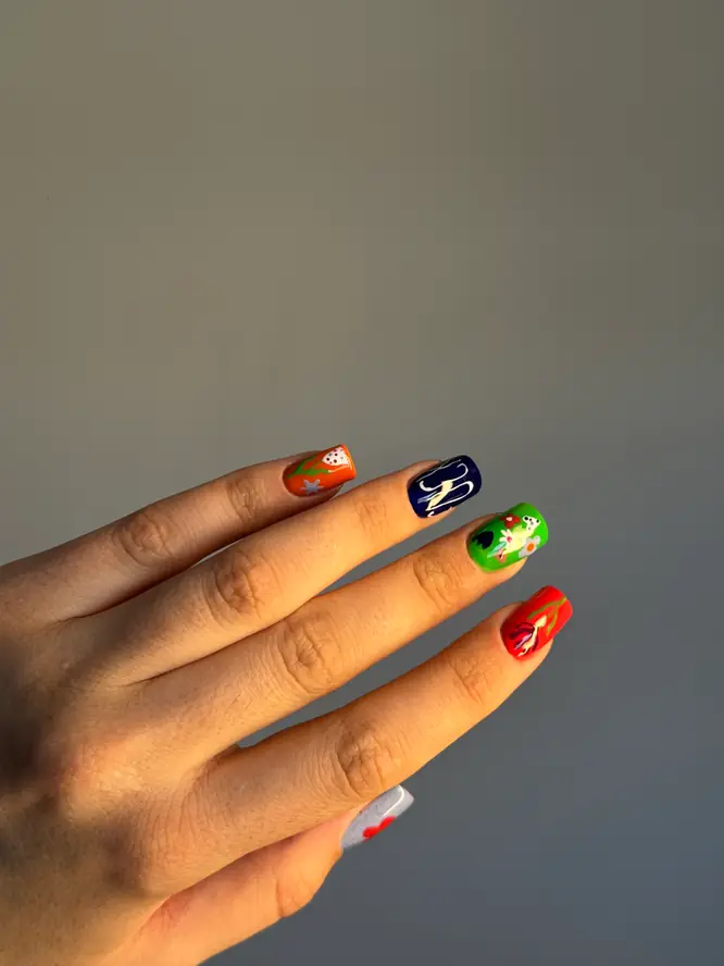 Hand-painted pin-up nail art on a colorful mix — orange, navy, green and red, client work.