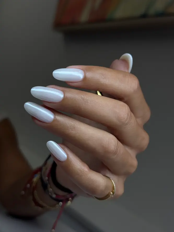Milky-white gel on almond nails — studio close-up, client work.