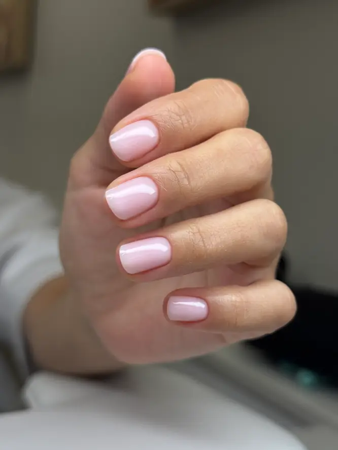 Sheer pink gloss on natural short nails — clean everyday gel manicure, salon work.