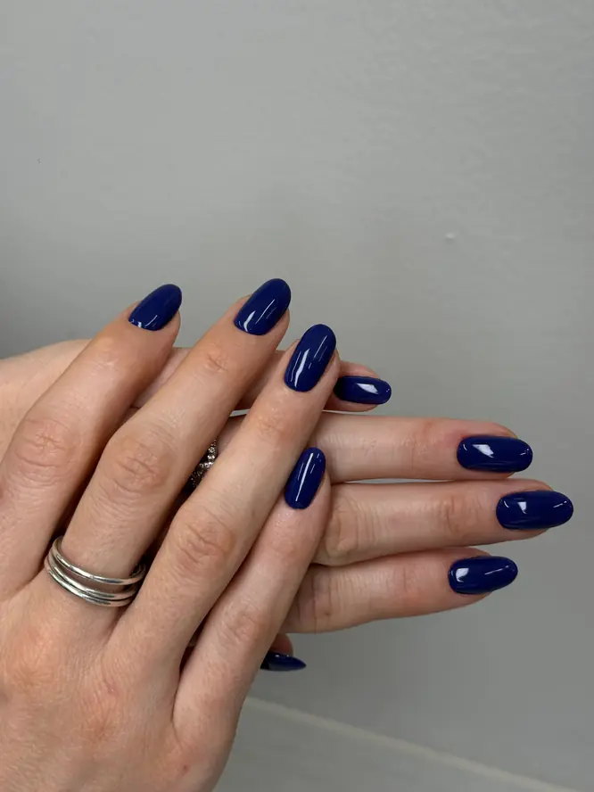 Deep navy-blue gel manicure on round nails, both hands — client work.