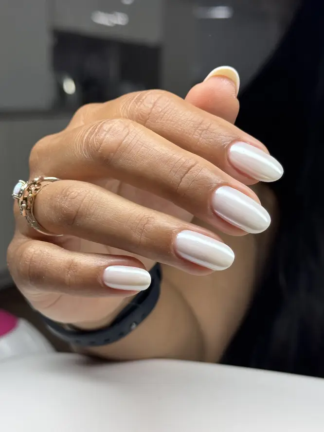 Pearl-white chrome gel on almond nails with an opal ring — client work.